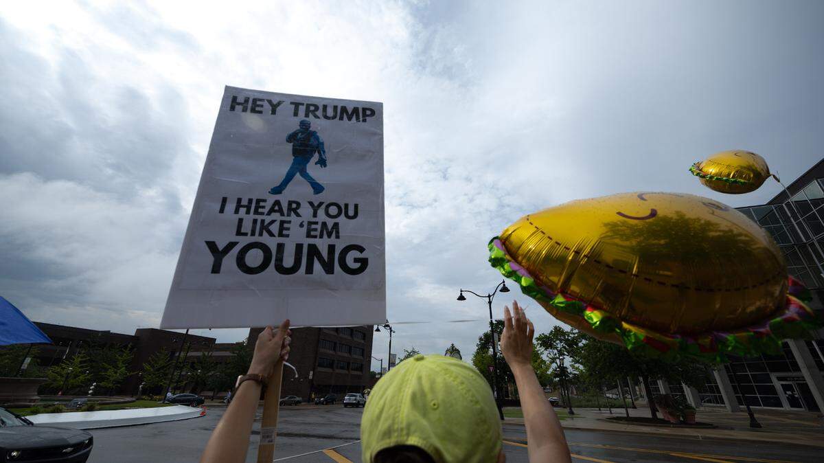 A protestor holds up a sign saying “Hey Trump, I hear you like ‘em young,” an allusion to the Kendrick Lamar song “Not Like Us” and the controversy surrounding the Trump administration’s handling of the Epstein files.