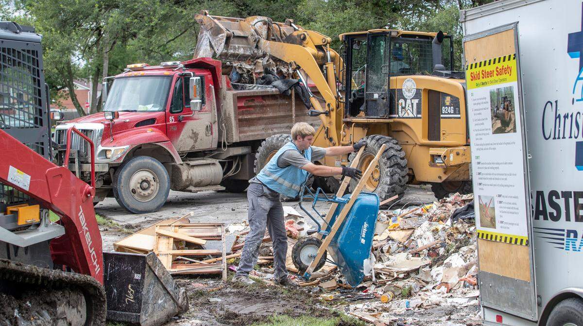 An East St. Louis front loader dumps flood damaged debris into a dump truck as a volunteer with Christian Aid Ministries rapid response team empties flood damaged drywall and other items. Volunteers from Christian Aid Ministries, Municipal Solutions & Services, and other organizations helped the city of East St. Louis workers remove debris from the flood damaged neighborhood on Terrace Dr. and Mary Ave. in East St. Louis on Thursday.