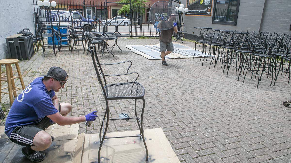 Gabe Schneider repaints furniture at Big Daddy’s 618 in preparation for a patio reopening this weekend with bar service only. Customers can temporarily bring in food from other local restaurants.