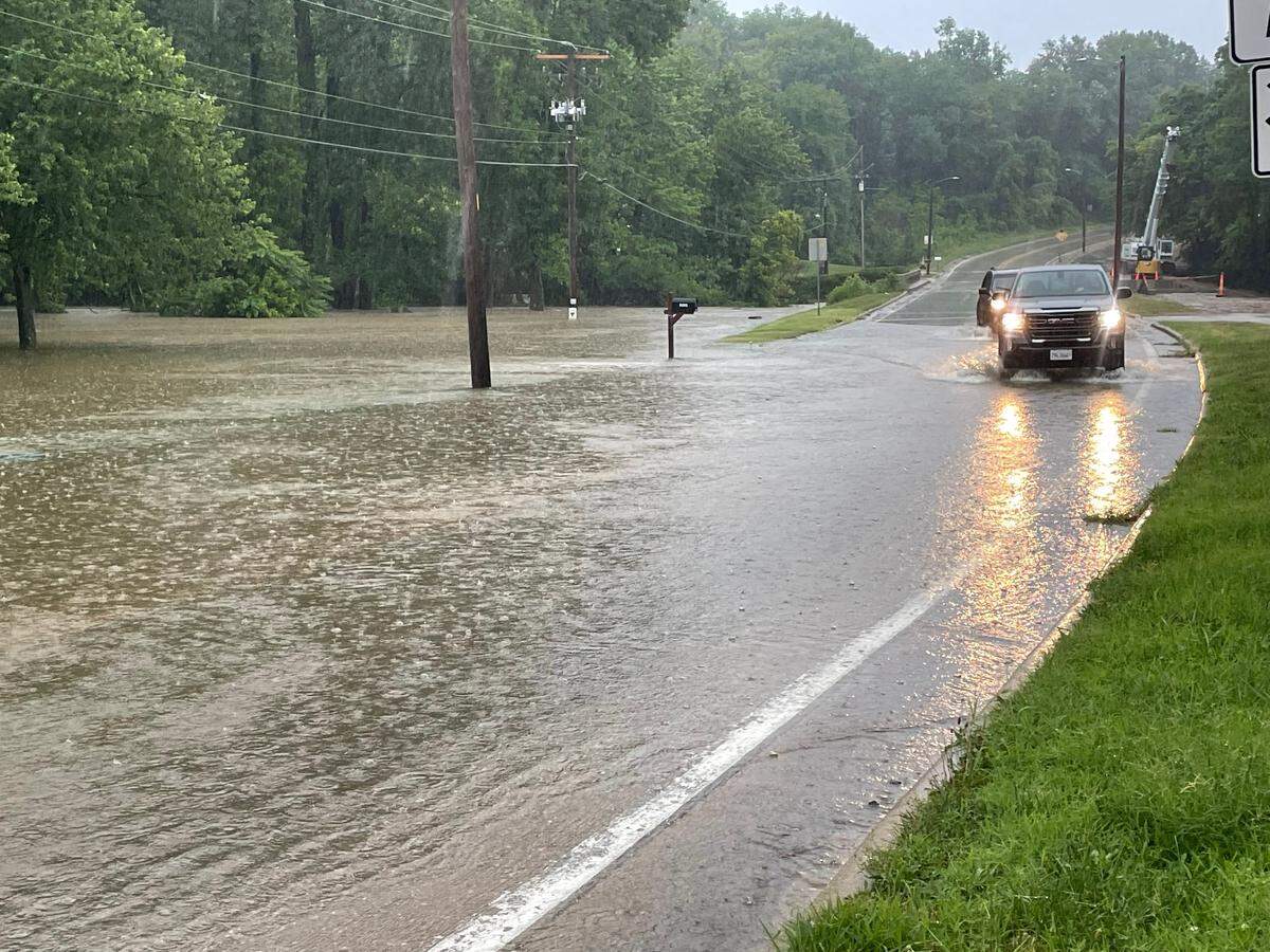 Drivers navigate water backed up over Old Collinsville Road near the Lake Lorraine subdivision in Swansea Tuesday.