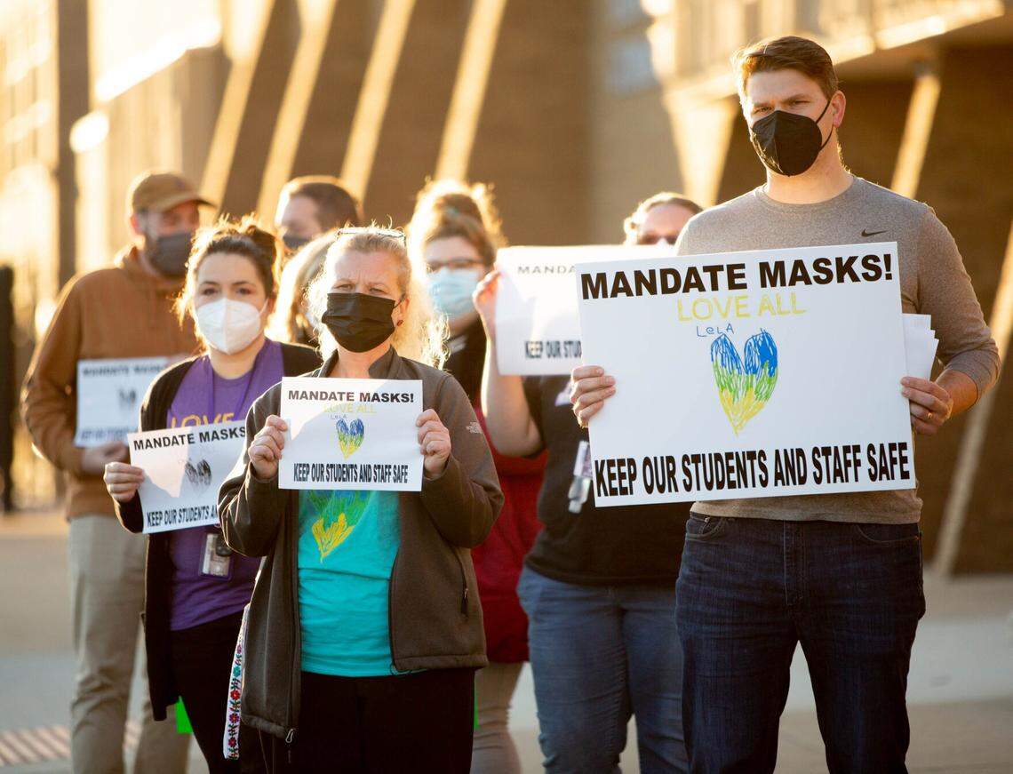 Jacob Post, a special education teacher at Collinsville High School, at right, calls for the district to uphold its mask mandates to protect medically vulnerable students, like his daughter Lela, last month before a school board meeting at Collinsville High School in Collinsville.