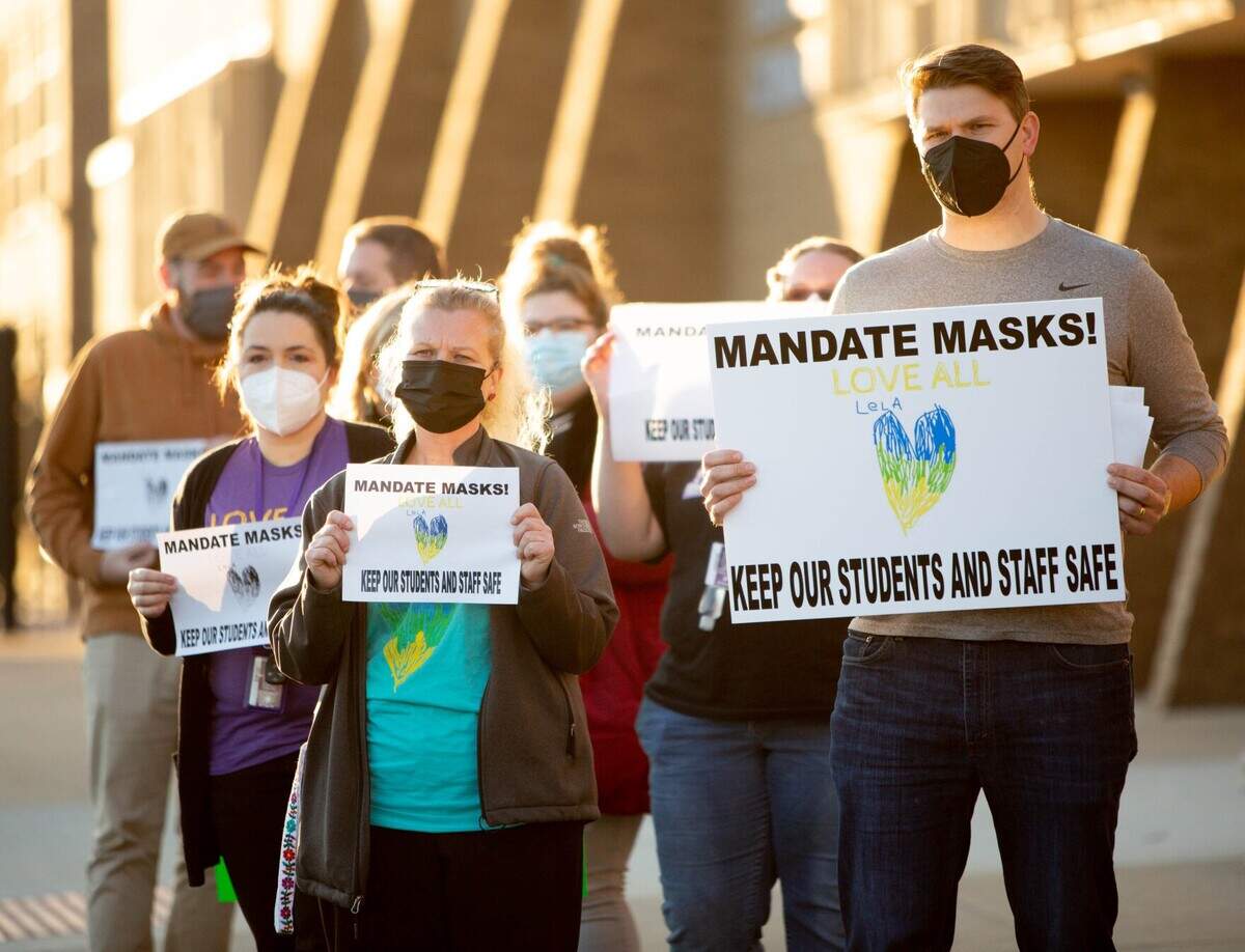 Jacob Post, a special education teacher at Collinsville High School, at right, calls for the district to uphold its mask mandates to protect medically vulnerable students, like his daughter Lela, last month before a school board meeting at Collinsville High School in Collinsville.