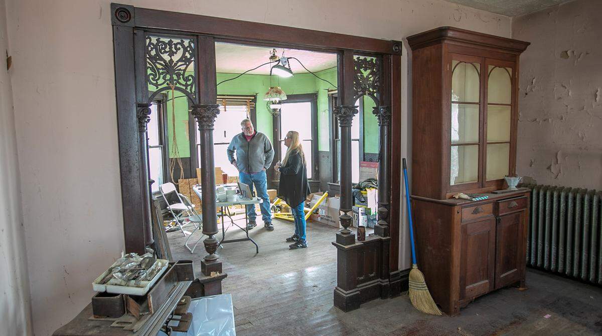 Mike Kuhl, left, owner of “The Pink House” in Aviston, talks to Vickie Gentz, who grew up in the home in the 1960s and ’70s. They’re standing in the foyer, which once doubled as a barbershop.