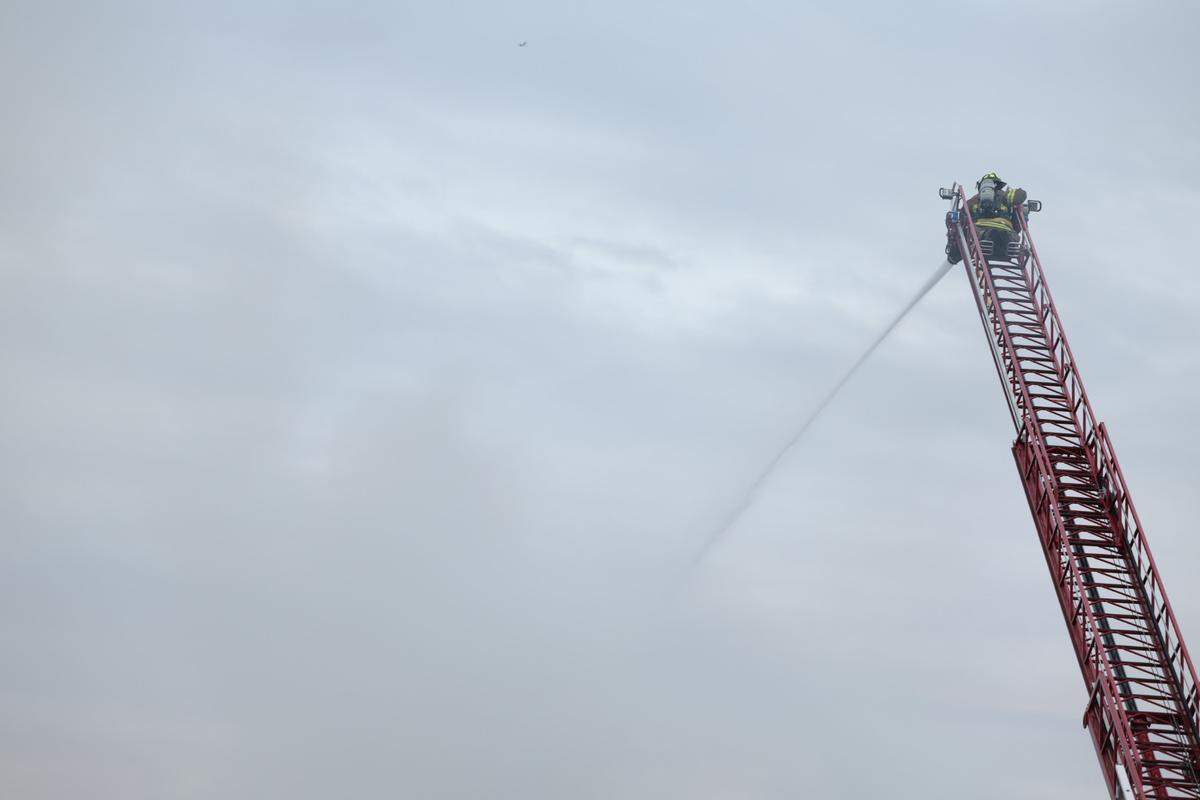 A firefighter works from high on a hook-and-ladder truck to extinguish a fire at the Millstadt wastewater treatment facility Tuesday afternoon.