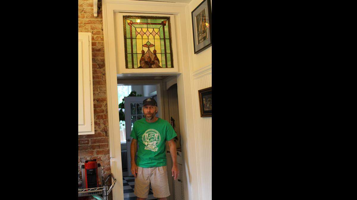 Chad McCullough passes under a stained-glass window above the doorway to the kitchen in his 1874 brick home on Abend Street in Old Belleville Historic District.