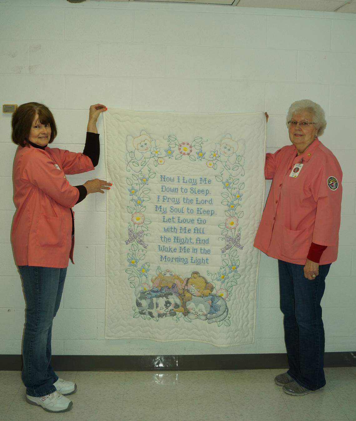 'Now I Lay Me Down to Sleep' quilt displayed by Joann Timmermann, left, and Ann Olliges, right, for the June 21 St. Joseph's Hospital Auxiliary quilt raffle.