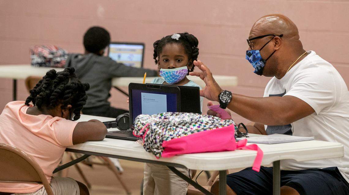 Volunteer Cortillian Andrews, who has a background in early elementary education, helps students with their online classwork Mt. Sinai Family Center in East St. Louis. Andrews says part of the challenge is helping the children communicate with the teachers and making sure they don’t get frustrated.