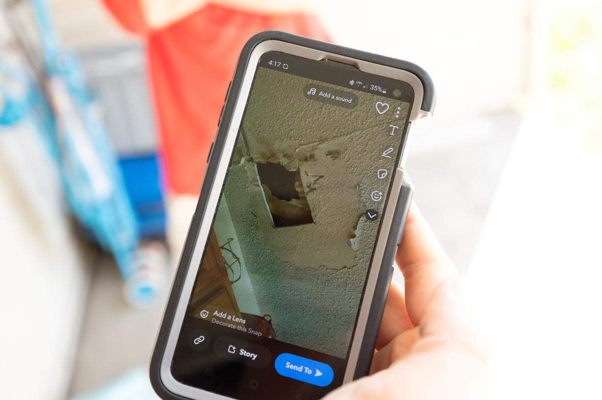 Centreville Courts resident Vikki Monroe shows a photo on her phone of damage in her apartment that the landlord hasn’t fixed. Leaking pipes caused a hole to form in the ceiling of her kitchen.