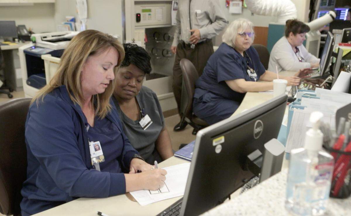 Nurses and staff members work at one of the nurse stations at Memorial Hospital in Belleville.