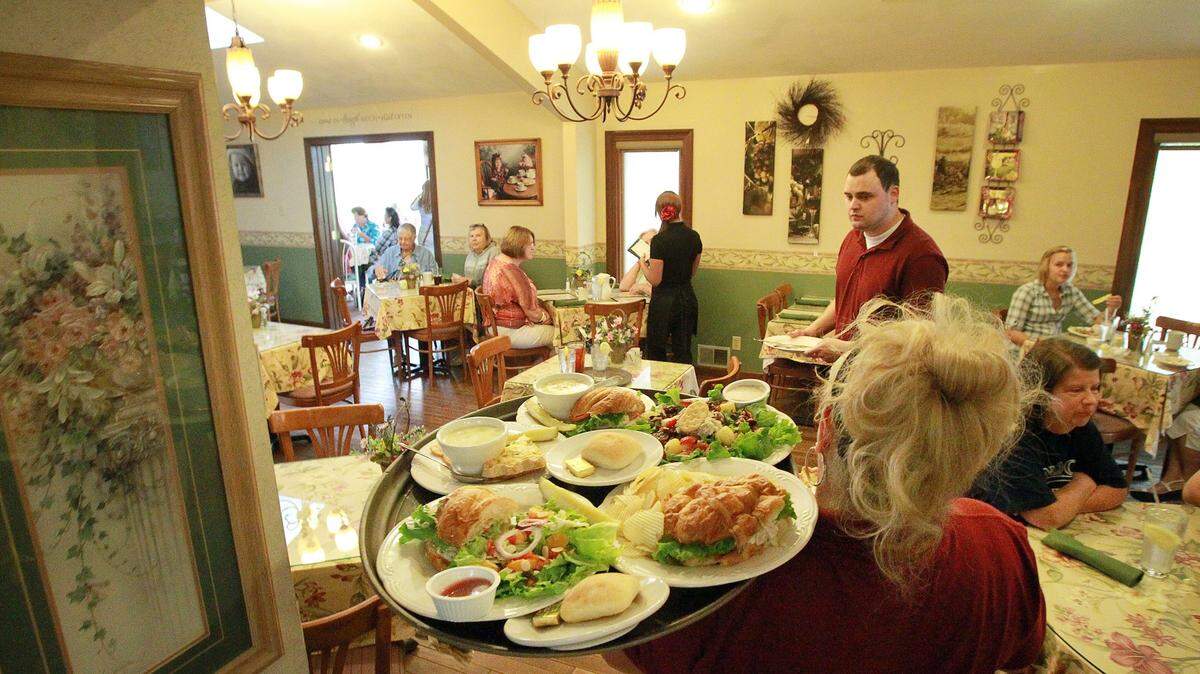 Waitress Kathy Mardirosian carries a tray of food in 2013 through the dining room at Rachel's Garden. The restaurant will close in April.