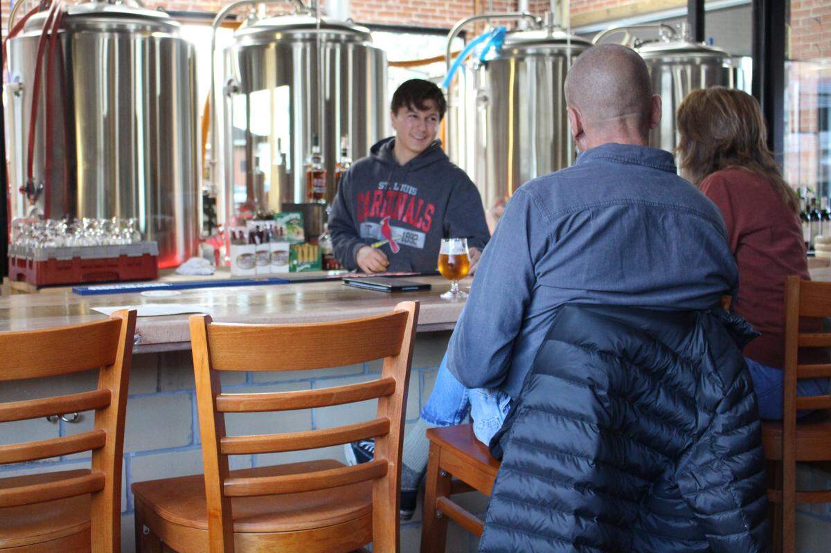Bartender Brett Gutierrez serves customers at Millpond Brewing & Incubator in Millstadt. The beer-making operation can be viewed through a glass wall.