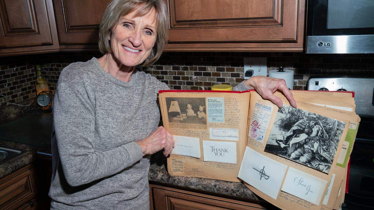 Mary Becker Schaefer poses with a scrapbook, the left page showing a scene of her and her brother at Belleville’s former Cathedral elementary school.