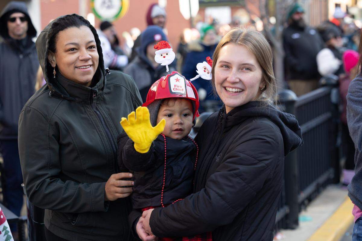 A child and his parents happily wave as Santa arrives on the scene.