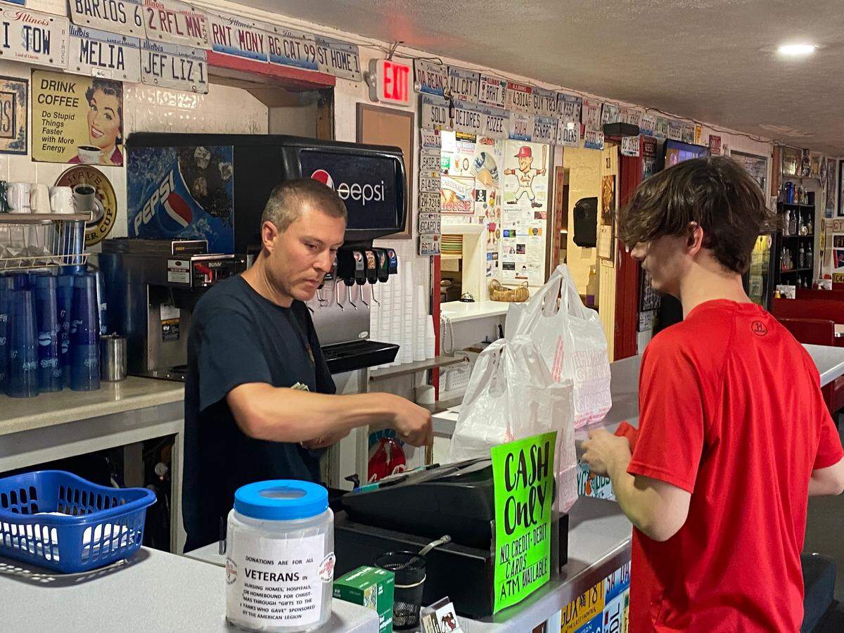 Michael DeBruce, left, serves a customer in the Park Grill restaurant he owns in Granite City near the steel mill where nearly 1,000 workers could lose their jobs. “It’s going to be bad, there’s no other way around it,” he said.