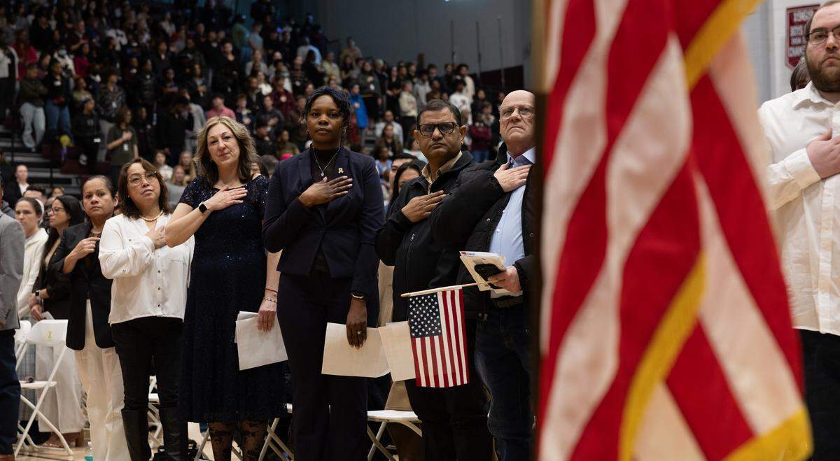 Soon-to-be U.S. citizens get ready to recite the Pledge of Allegiance for the first time on Friday at Belleville West High School.
