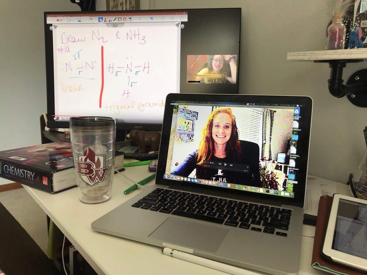 Elisabeth Knierim, a chemistry teacher at Belleville West High School, appears on her laptop screen in a recorded video memo. The large monitor shows notes from her iPad and a student responding to a question.