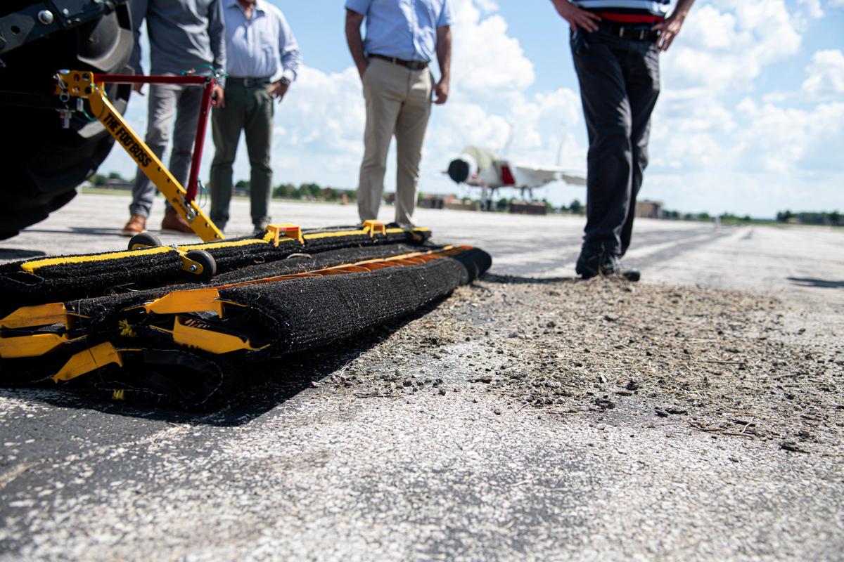 A mat designed to pick up foreign objects and debris sits affixed to an autonomous tractor in front of a pile of collected FOD on Scott Air Force Base. The FOD was collected as part of an operational demonstration of two autonomous tractors through a partnership between Elevate — Scott’s innovation cell — and Sabanto Agriculture.