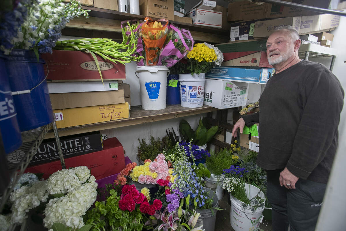 Jeff Bair, co-owner of Grimm & Gorly Flowers & Gifts in Belleville, stands next to containers of flowers for a Friday night wedding that was canceled due to the coronavirus pandemic.
