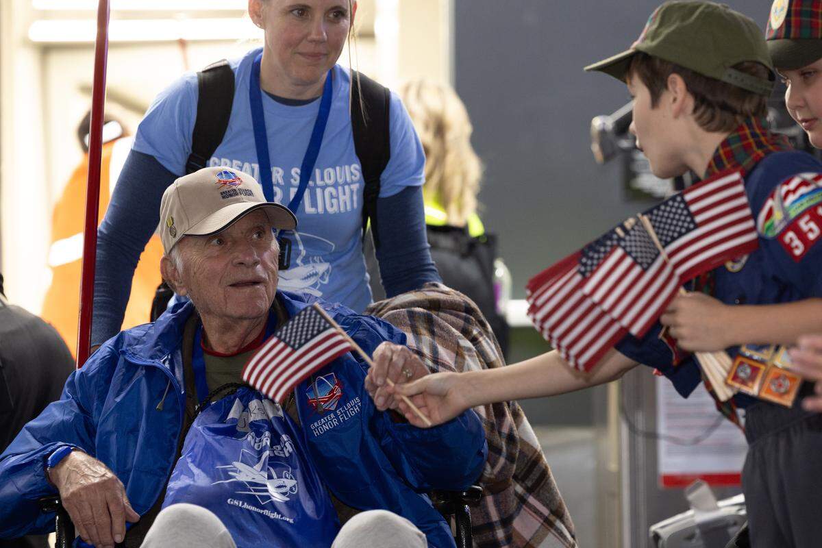 A veteran receives an American flag from a Boy Scout after disembarking from the Greater St. Louis Honor Flight.
