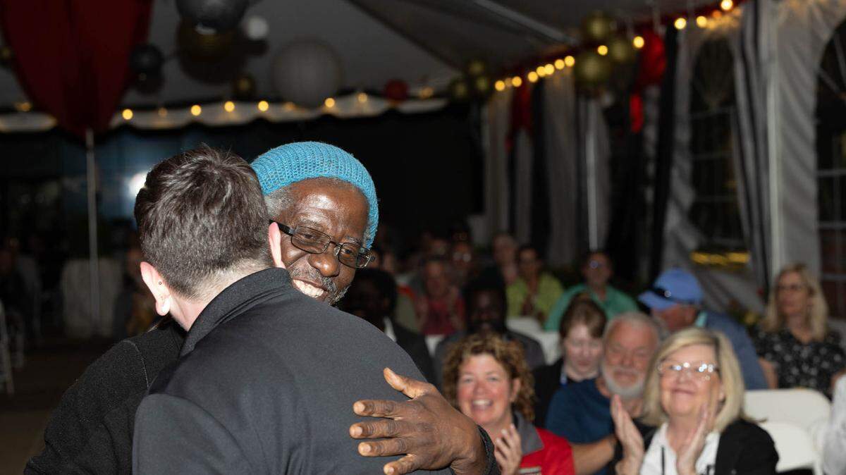 William Kwamena-Poh hugs Art on the Square volunteer Jesse White after winning the award for Best of Show.