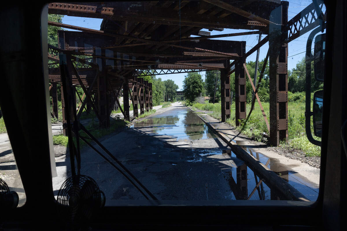 The bus drives through an underpass still filled with standing water from rain the day before.