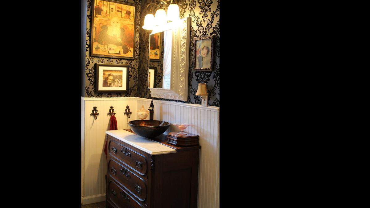 The upstairs bathroom in the McCullough family’s 1874 brick home on Abend Street in Old Belleville Historic District has textured wallpaper, wainscoting and an antique vanity.