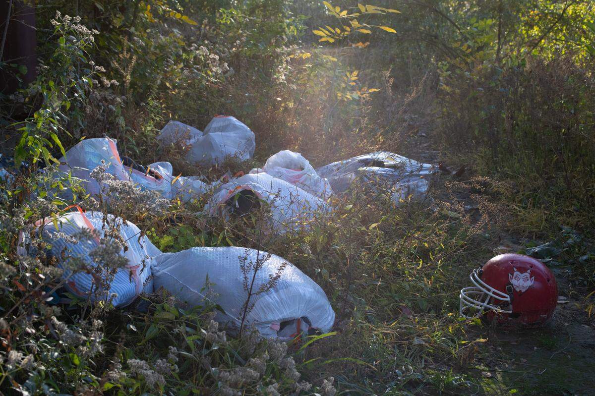 A football helmet stands out among bags of items left in woods near North End Park last week. It’s one of several Belleville locations where people have been camping illegally.