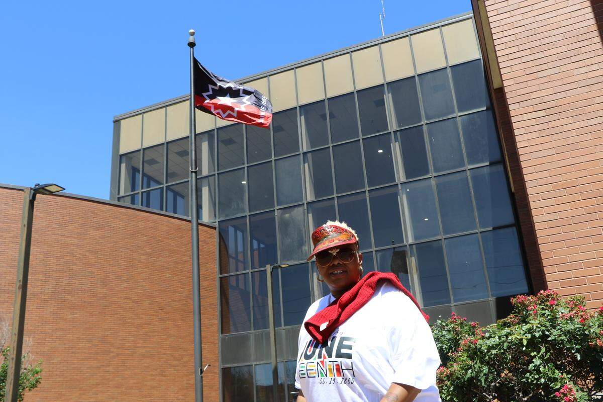 Terra “T-Baby” Jenkins poses in front of the Junteenth flag at the East St. Louis municipal building Saturday.