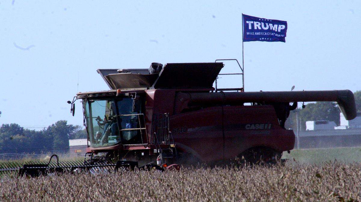 A farmer flies a flag in support of Donald Trump in 2016 as he combines soybeans near Highland.