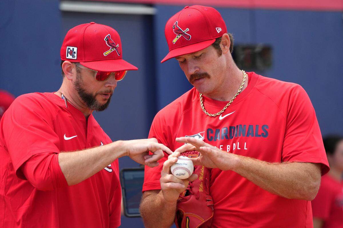Feb 12, 2025; Jupiter, FL, USA;  St. Louis Cardinals St. Louis Cardinals pitcher Miles Mikolas, right, goes over his grip with pitching coach Dusty Blake during Spring Training. Mandatory Credit: Jim Rassol-Imagn Images