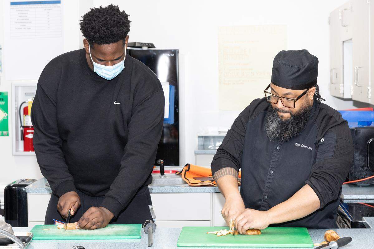 Culinary instructor Gregory Clemons shows a student at East St. Louis Senior High School a technique for cutting vegetables.