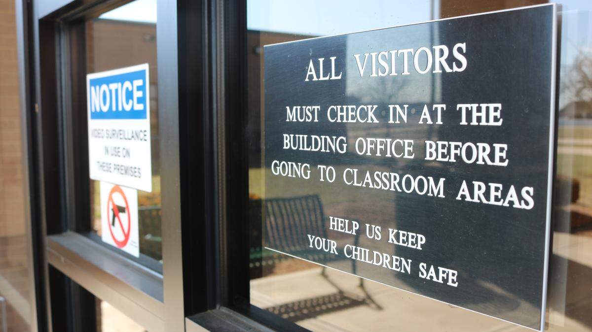 A sign at Highland Middle School asking visitors to check in at the front office before entering the school, which is a precaution used for safety measures.