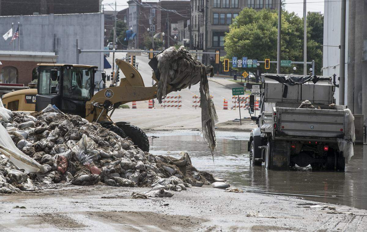 As floodwater slowly creeps back into Mississippi work crews remove sandbags and a temporary flood wall as cleanup efforts continue in downtown Alton.