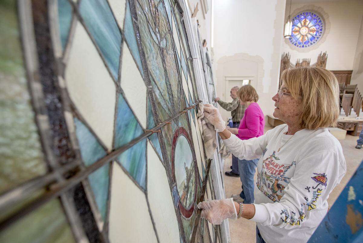 Debbie Lippert, Julie Harris and Jack Snyder work to remove years of grime and dust that collected on three of four stained glass windows that were put into storage at St. Paul United Church of Christ, Belleville, IL. The windows will be put back in their original location as the church restores the former sanctuary.