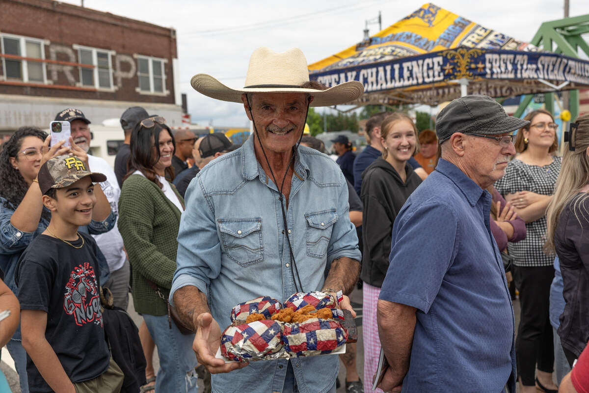 Big Texan Steak Ranch owner Bobby Lee brings a plate full of steak, baked potatoes, shrimp cocktails, and tossed salads to waiting contestants.
