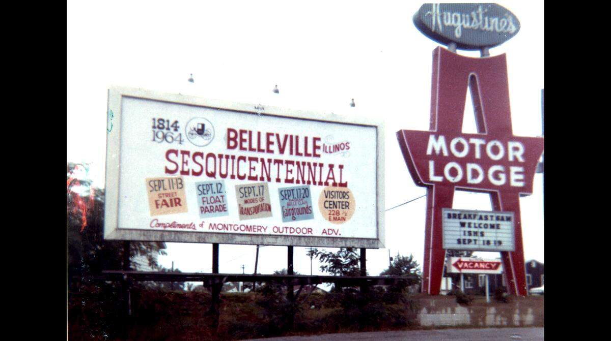 Augustine’s Motor Lodge sign next to a billboard about the 150th anniversary of Belleville.