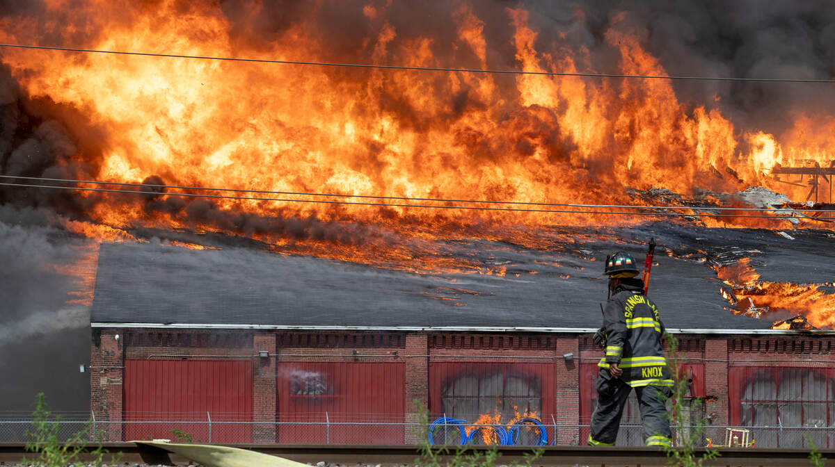 This 2022 photo won a first place award for spot news photography in the Illinois Press Association journalism contest. In it, a Spanish Lake firefighter carries wire cutters across a set of railroad tracks so firefighters can cut an access point in a fence. Firefighters from multiple agencies in Missouri and Illinois responded to a warehouse fire in Madison, Illinois. The smoke from the fire could be seen for miles.