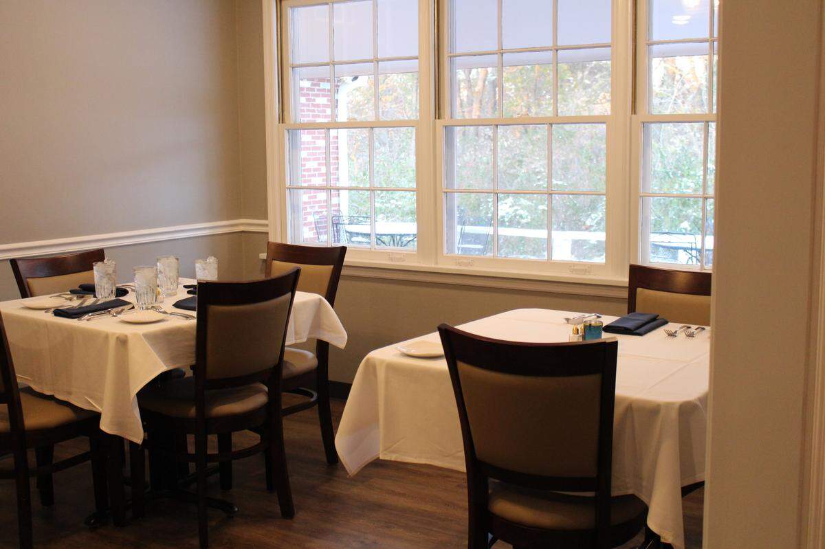 Tables are covered with white tablecloths in a small dining room that overlooks woods and a patio at Moussalli’s Prime on the outskirts of Edwardsville.