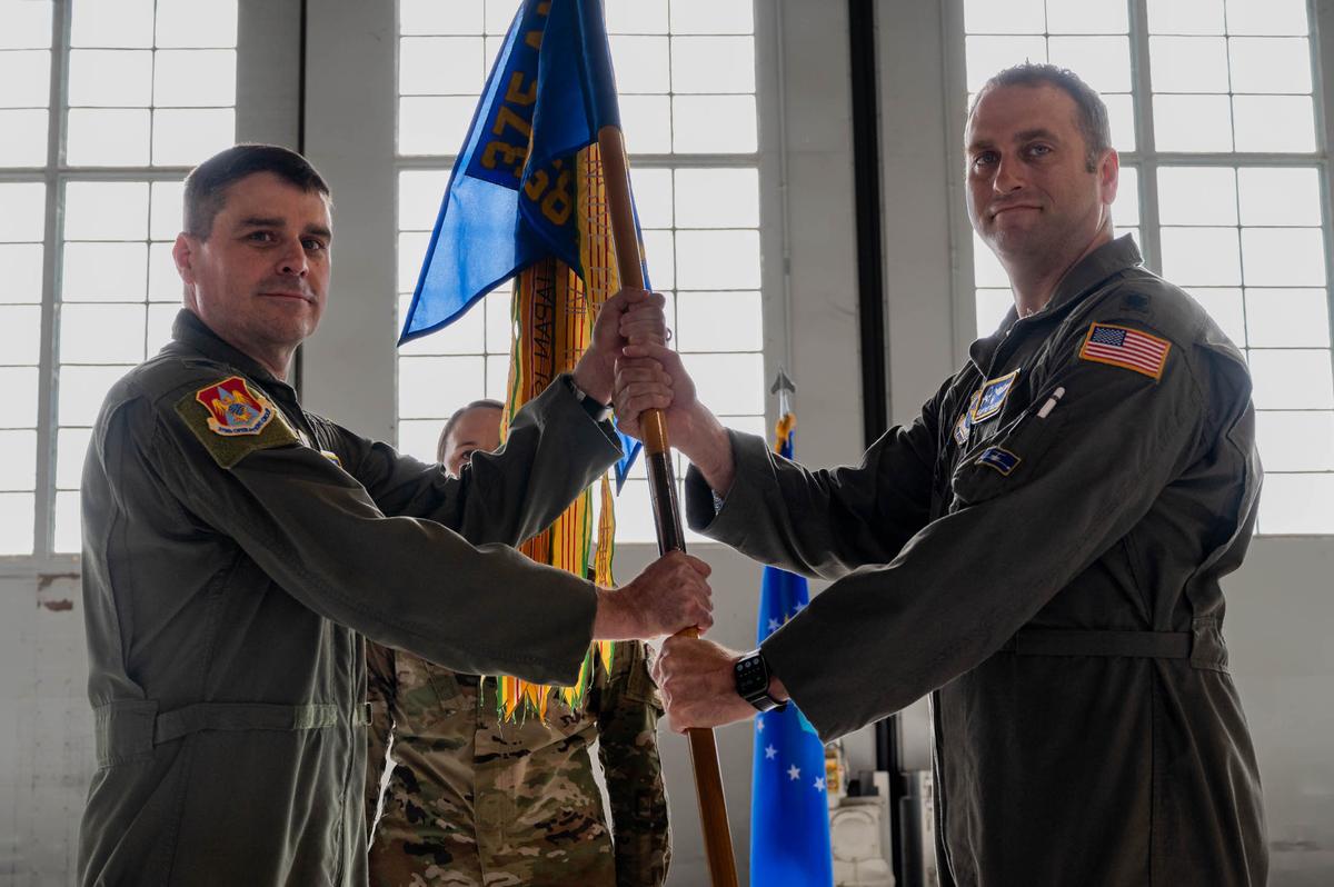 U.S. Air Force Col. Bradely Stevens, 375th Operations Group commander, hands guidon to Lt. Col. Geoffrey Goldsmith, 458th Airlift Squadron command, during the 458th Airlift Squadron change of command ceremony May 26 at hangar 3 on Scott Air Force Base. The ceremony represents a time-honored military tradition providing an opportunity for Airmen to witness the transfer of power to their newly appointed commanding officer.