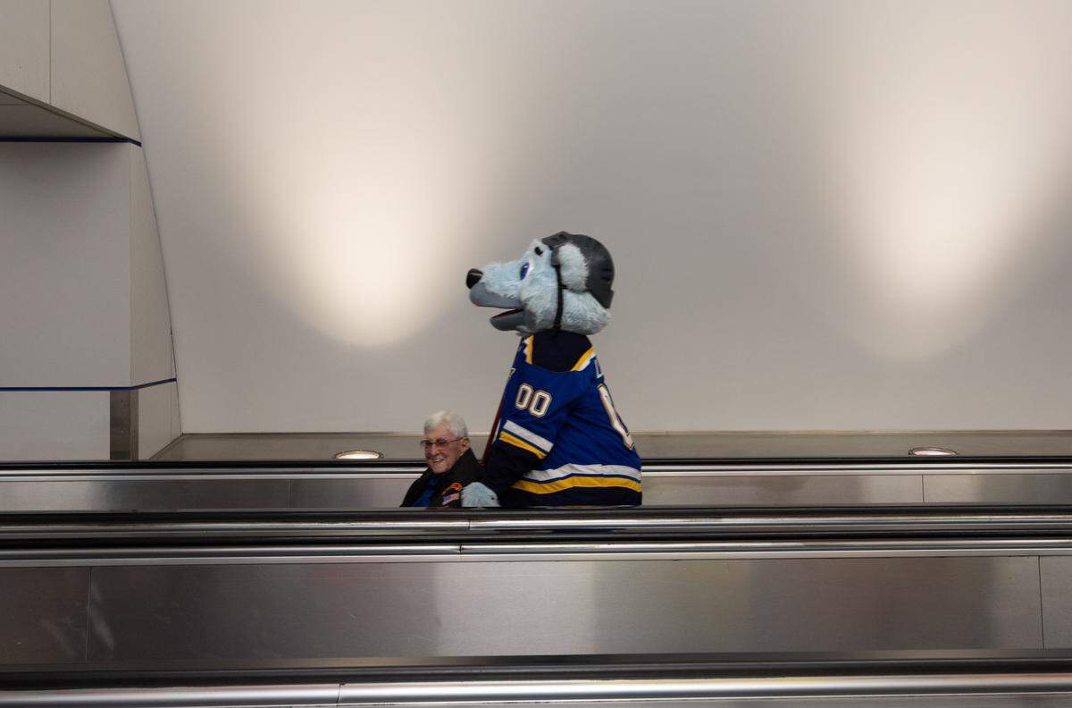 Greater St. Louis Honor Flight founder Harry Hope, a Korean War veteran, is pushed through the airport by St. Louis Blues escort “Bluey.”