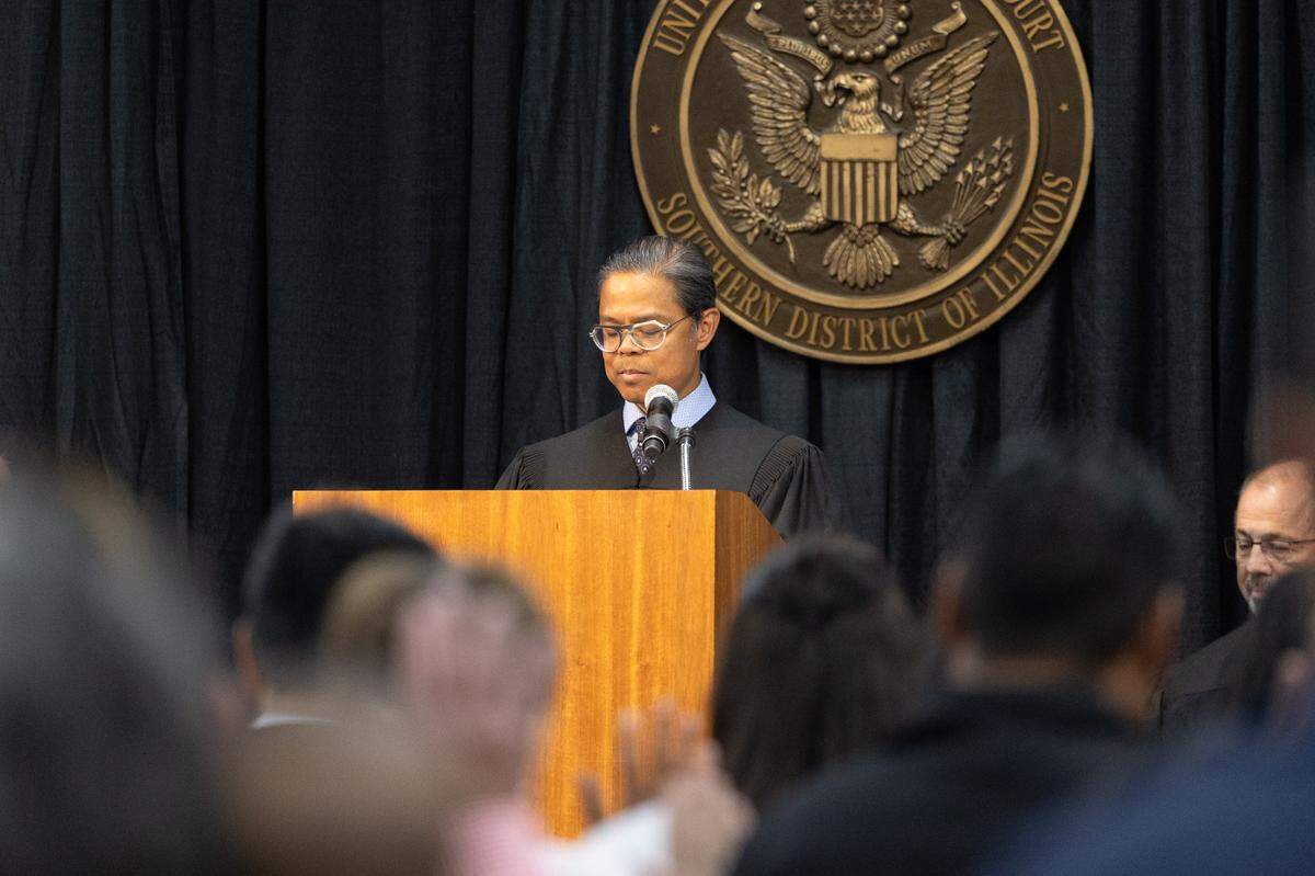 U.S. Magistrate Judge Gilbert Sison reads an oath to prospective new citizens during a naturalization ceremony in Collinsville.