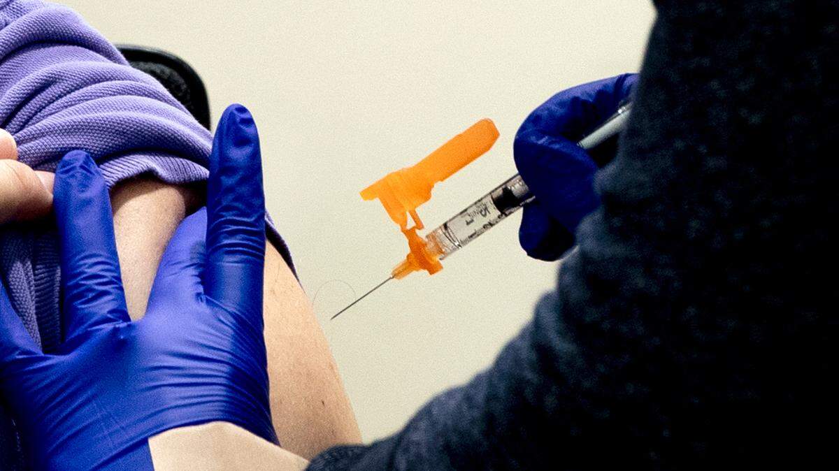 A nurse begins to administer a shot.