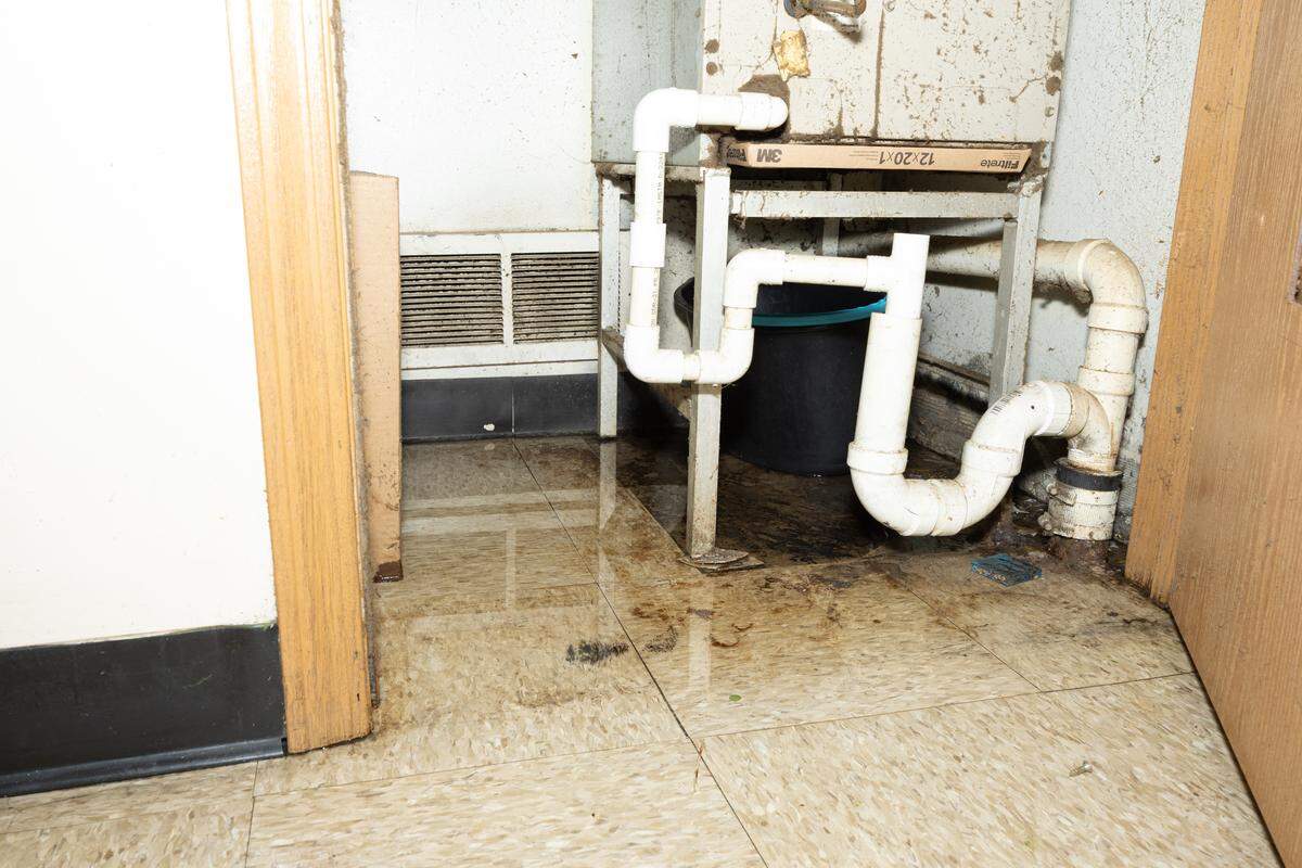 Water leaks from the furnace inside Twanna White’s home at Greystone Apartments. She and her son use a wet vacuum to remove water about five times a day because of the amount flooding into the living room, she said.