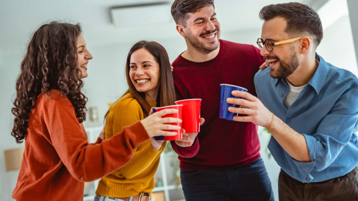 Coffee raves and sober morning events are bringing DJs, dancing and socializing into daylight hours. Group of young friends cheering with disposable cups, celebrating and having fun indoors