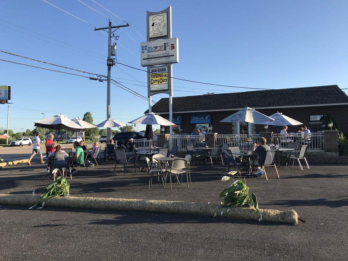 Fazzi’s Restaurant and Bar in Collinsville built a temporary patio in its parking lot with barriers made of hay rolled up in plastic netting and potted plants.