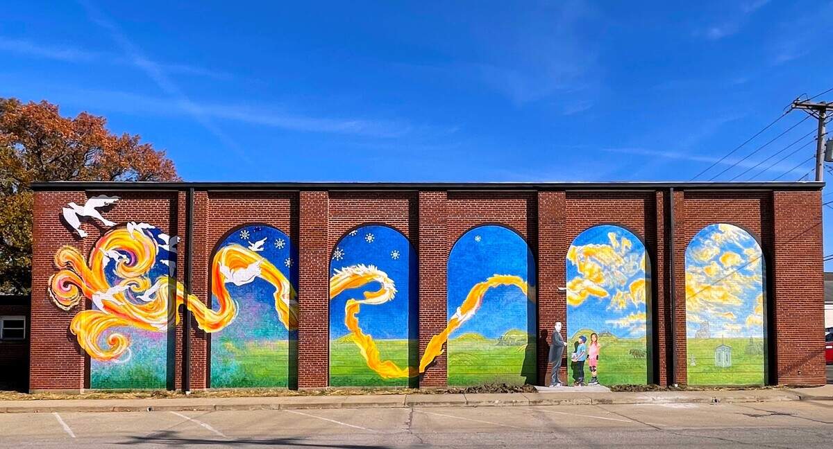 Made possible in part by a $10,000 matching grant from the National Endowment for the Arts, a mural was designed and painted on the side of the Weinheimer Community Center at the corner of Main and Pine Streets in Highland, by Robert and Liza Fishbone of On the Wall Productions from St. Louis. They were assisted onsite by Andy Cross (set painter for The St. Louis Muny Opera), and Lisa Roth. Deborah “Moe” Moellering painted the three cut out figures installed next to the mural.