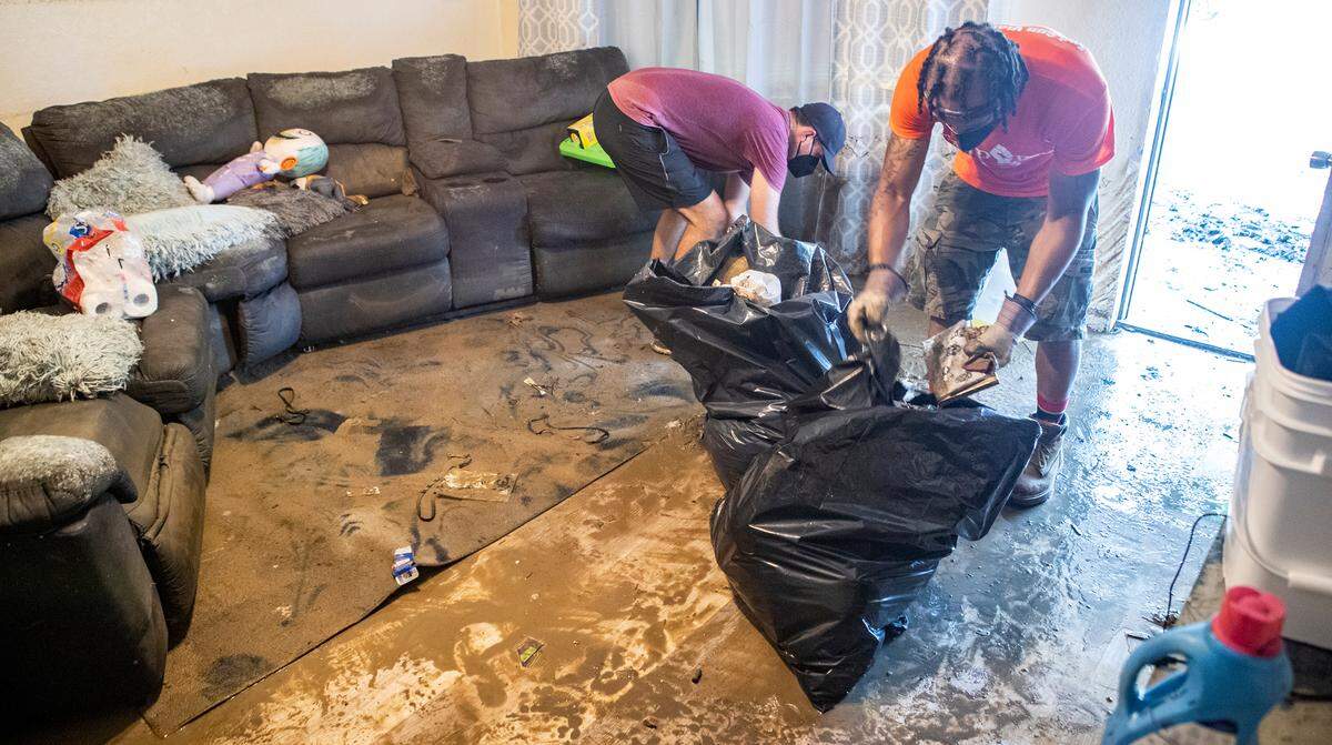 Kyle Mayberry and JD Dixon help pick up flood damaged items in an East St. Louis home. The volunteers with Empire 13 and We Are The People STL removed furniture, carpet, and other items from East St. Louis homes that were flooded.