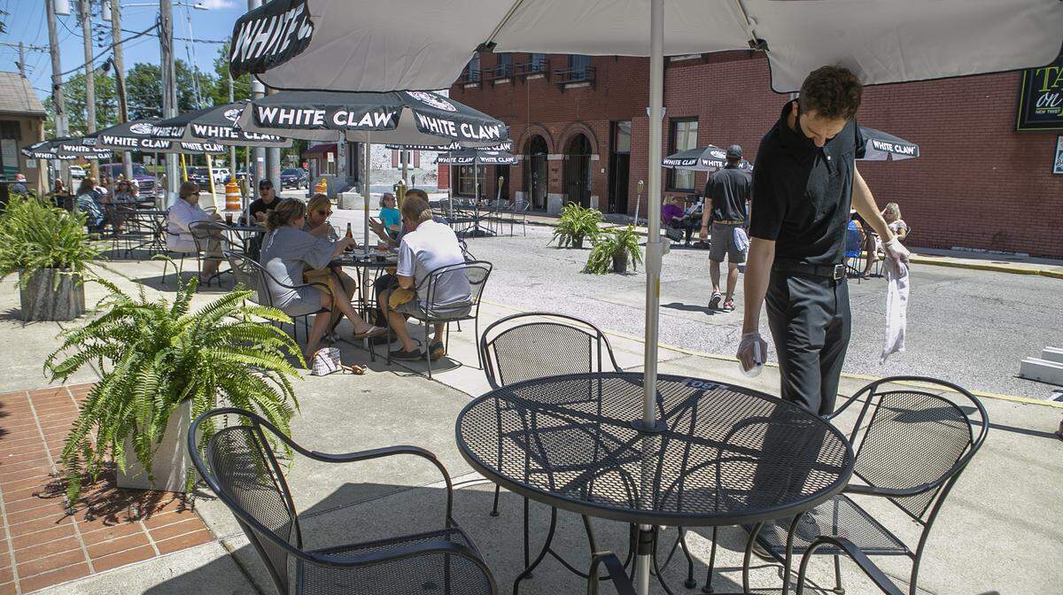 A Tavern on Main worker cleans a table and chairs in downtown Belleville on Friday, when restaurants were able to begin offering outdoor dining for the first time in more than two months.
