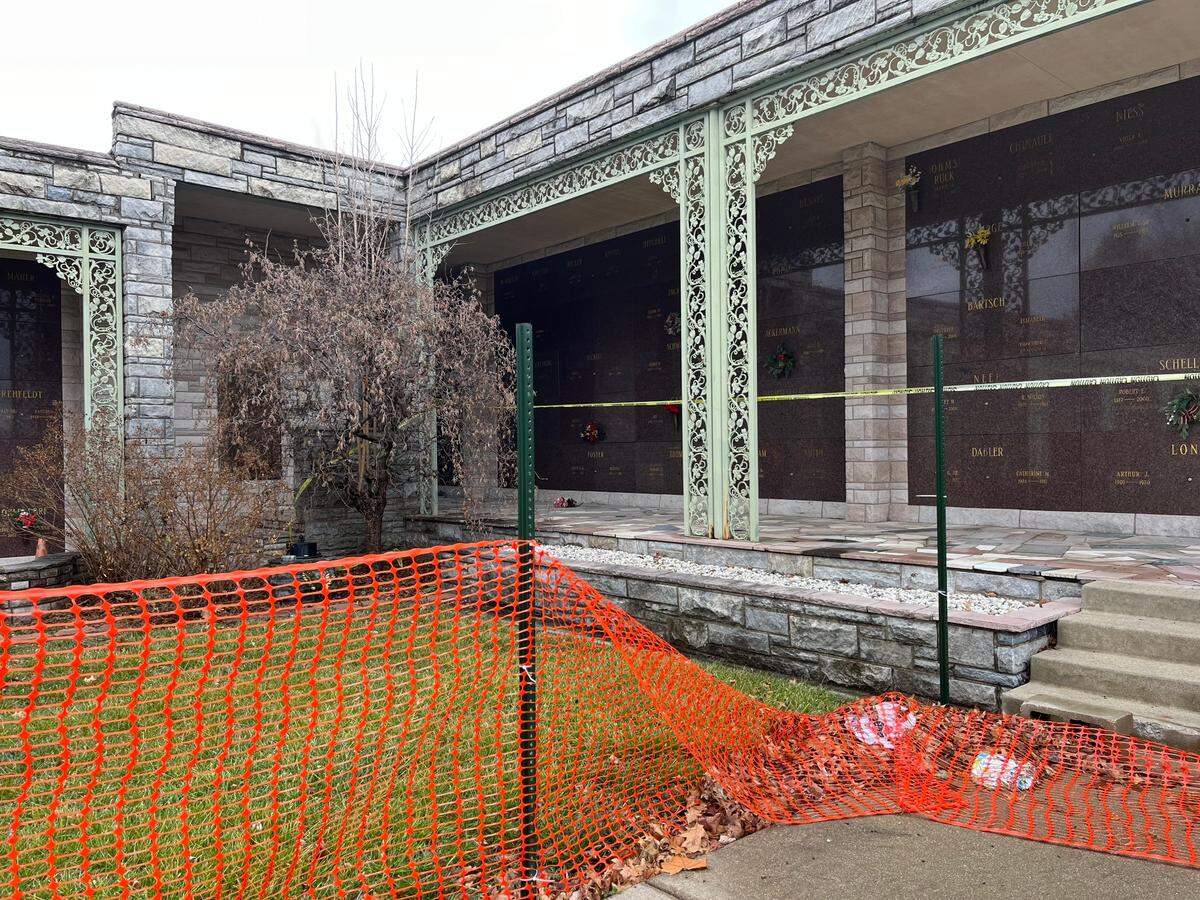 Trash is caught in orange plastic fencing around a mausoleum at Lake View Memorial Gardens in Fairview Heights. People have climbed over and trampled sections of the fence to visit crypts and fill vases with flowers.