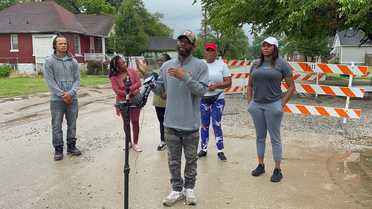 East St. Louis resident Darius Edwards talks at a news conference Saturday, July 9, 2022, about the moment his car sank into a hole in a city road while he watched outside the car. He and other residents and local activists stand in front of the hole, which was filled with gravel and blocked off to cars on Saturday.